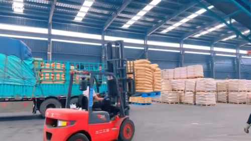 工厂厂区的产品装车现场，展示环保型猫砂产品即将发货。